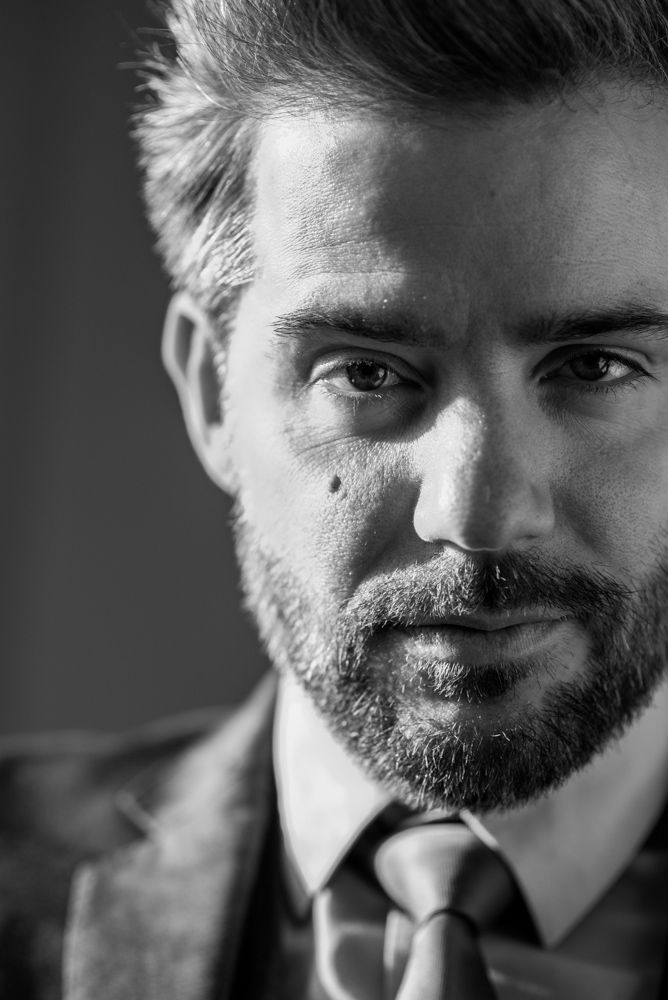 Black and white portrait series showing different facial expressions and angles of a bearded man in formal attire.