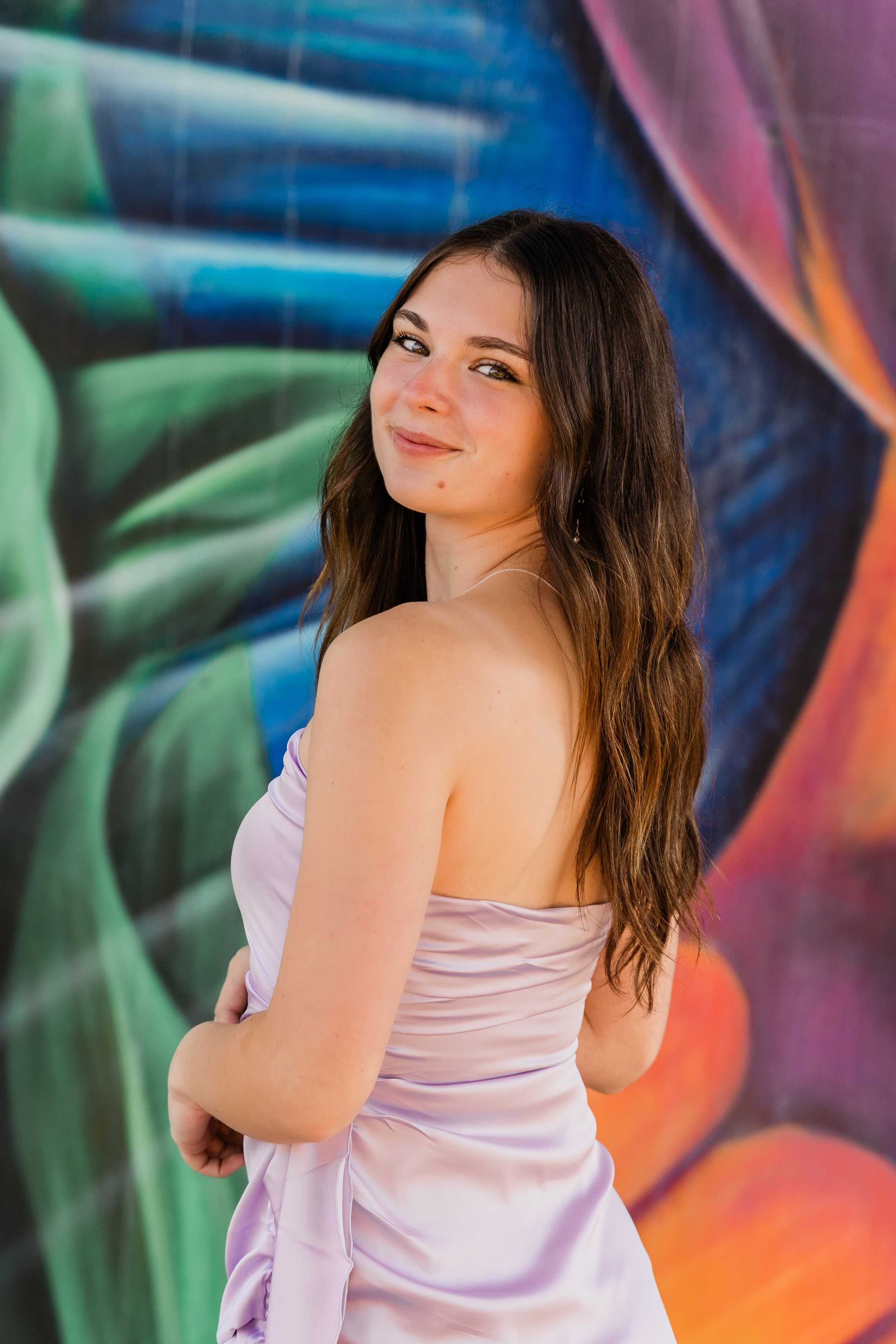 A series of fashion poses against a colorful graffiti wall in a lavender tank top.