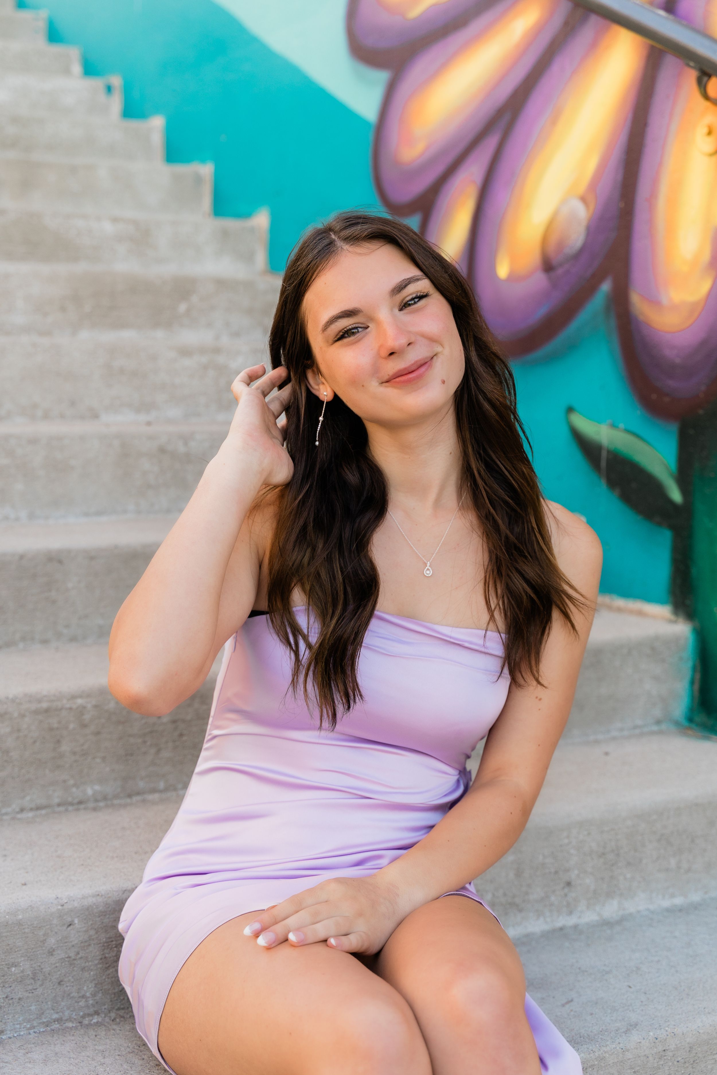 A photo series showing different poses on concrete steps with vibrant butterfly street art in the background.