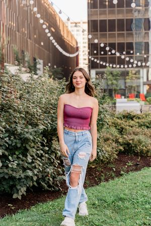 A fashionable outfit featuring distressed denim jeans paired with a burgundy top in an outdoor urban setting.