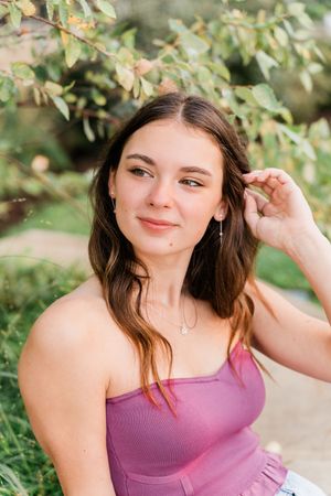 A woman in a purple tank top poses outdoors against a natural green foliage background in a series of candid shots.