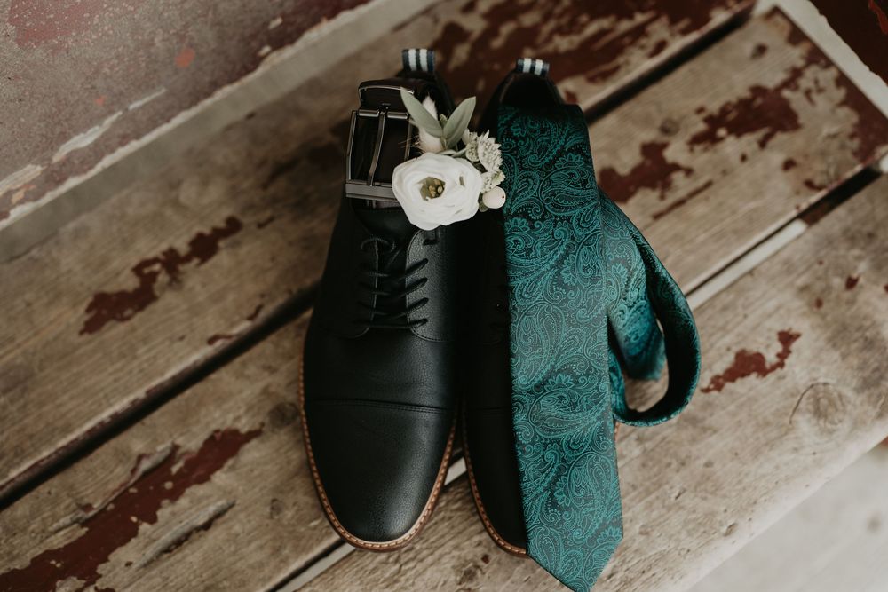 detail shot of groom's shoes, boutonnière and green paisley tie