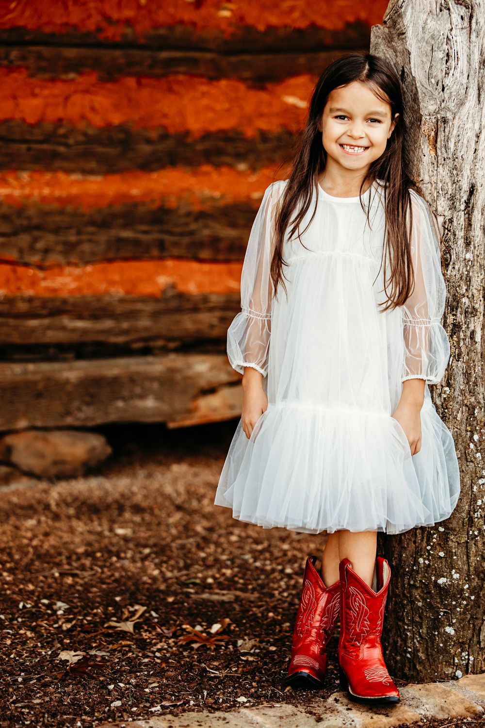 A white dress contrasts beautifully with bright red glitter boots against a rustic autumn background.