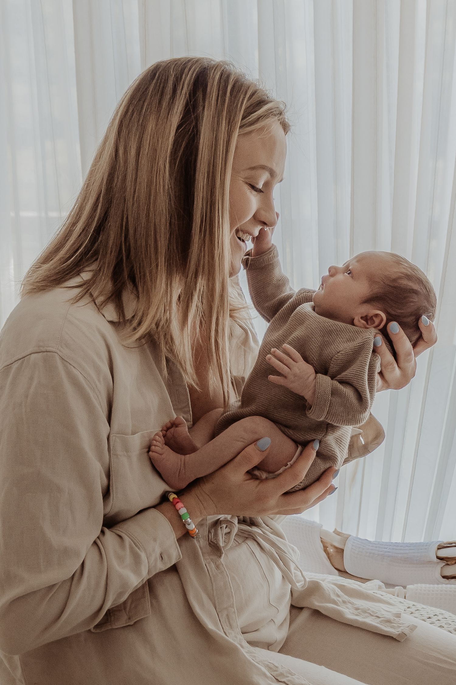 Tender moment captured showing a new mother and her baby sharing an affectionate interaction during a central coast newborn session.