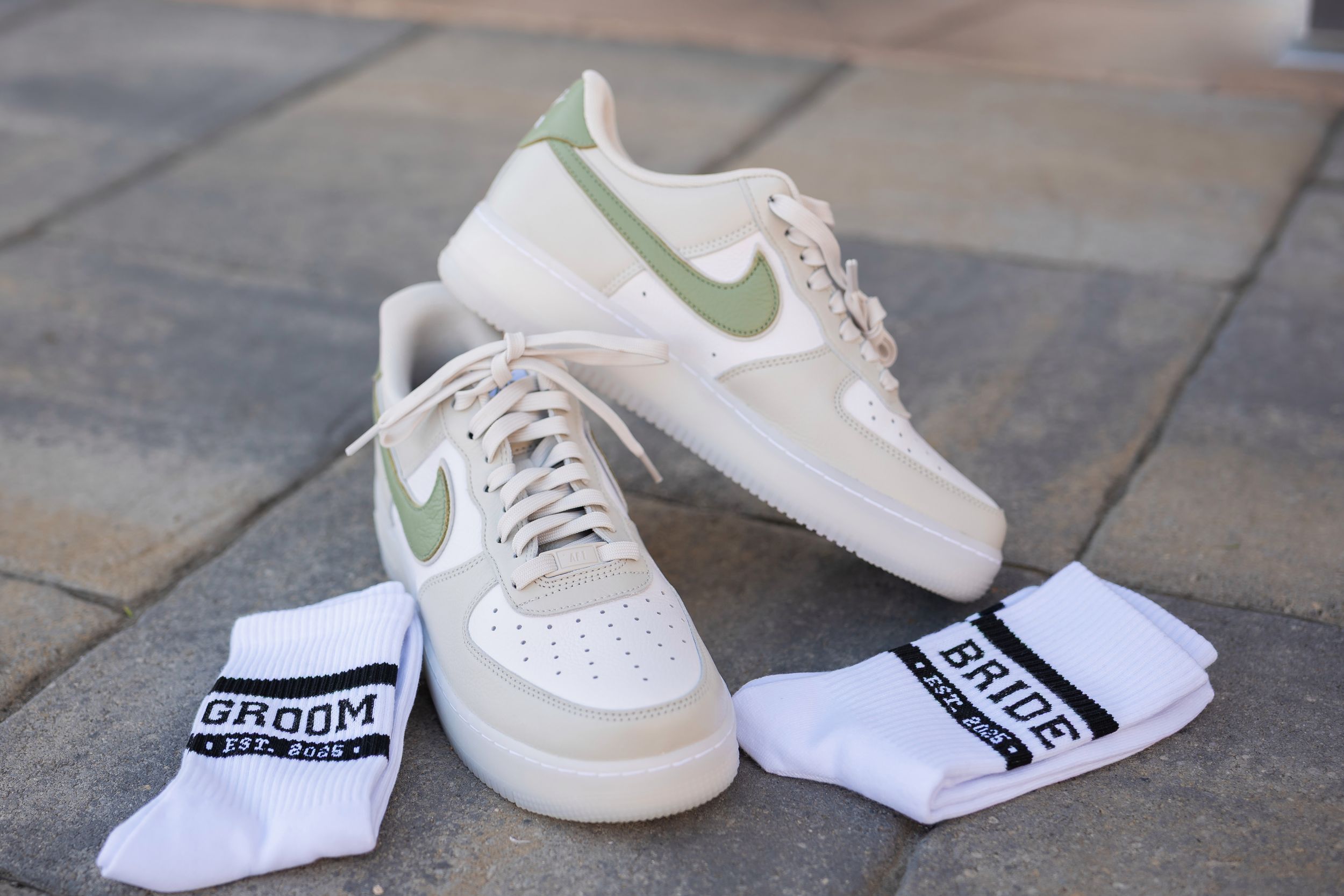 White Nike sneakers with green accents shown from multiple angles on a gray stone surface.