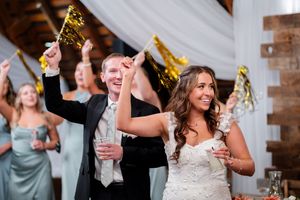 Wedding guests celebrate with sparklers and champagne during a joyful reception celebration at a rustic venue.