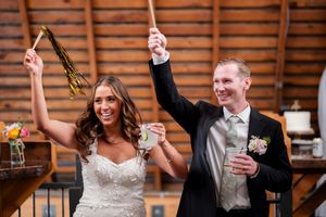 Newlyweds celebrate with champagne toasts at a rustic wooden barn reception venue.
