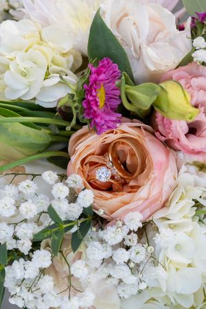 A close-up panorama of a romantic floral arrangement with peach roses, white baby's breath, and pink blooms.