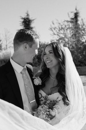 A romantic black and white wedding photo series showing tender moments between newlyweds with a flowing veil.