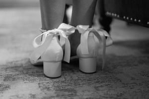 Monochrome close-up of white baby shoes arranged in a row on a textured surface.