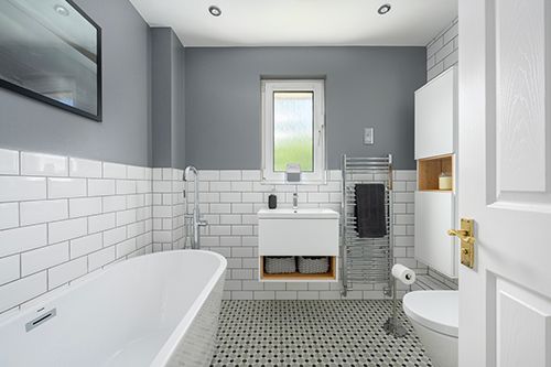Modern bathroom interior with white subway tile walls, gray hexagonal floor tiles, and recessed lighting fixtures.