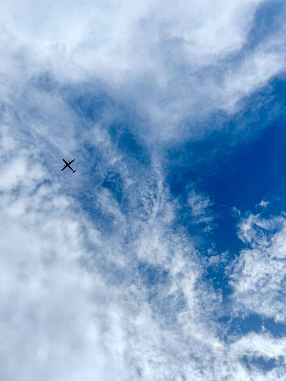 White wispy clouds float across a vibrant blue sky on a sunny day.