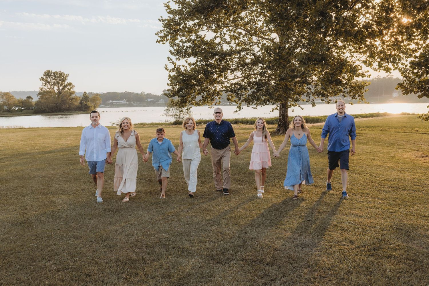 A loving family embraces together in a field of tall golden grass during an outdoor photo session at sunset.