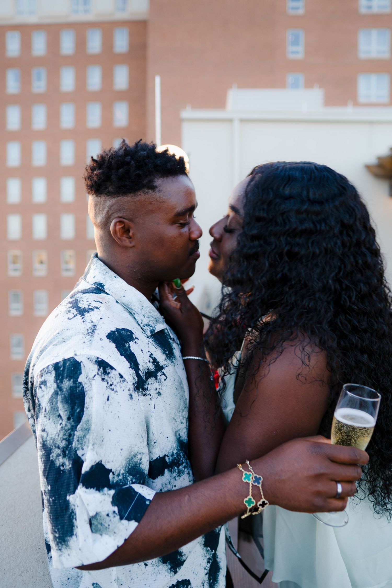 A couple shares an intimate moment while holding champagne glasses in a series of four connected photos.