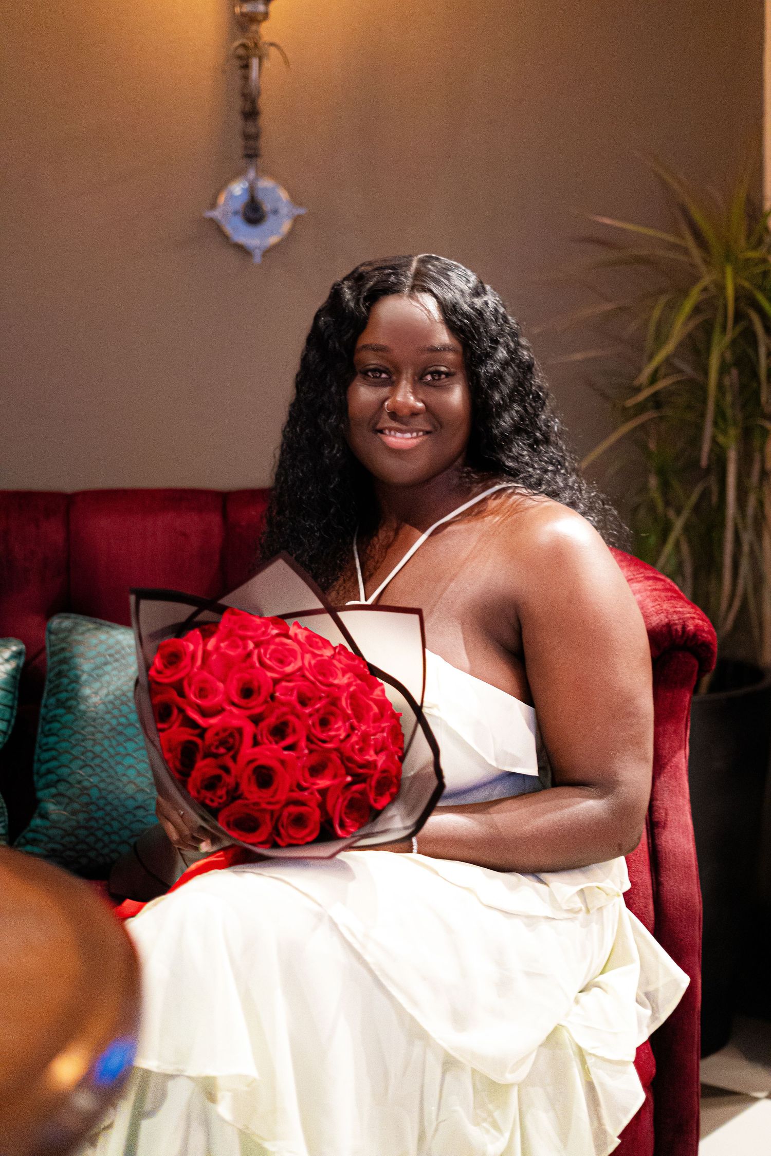 A person in a red and white dress poses elegantly on a couch for a glamour photoshoot series.