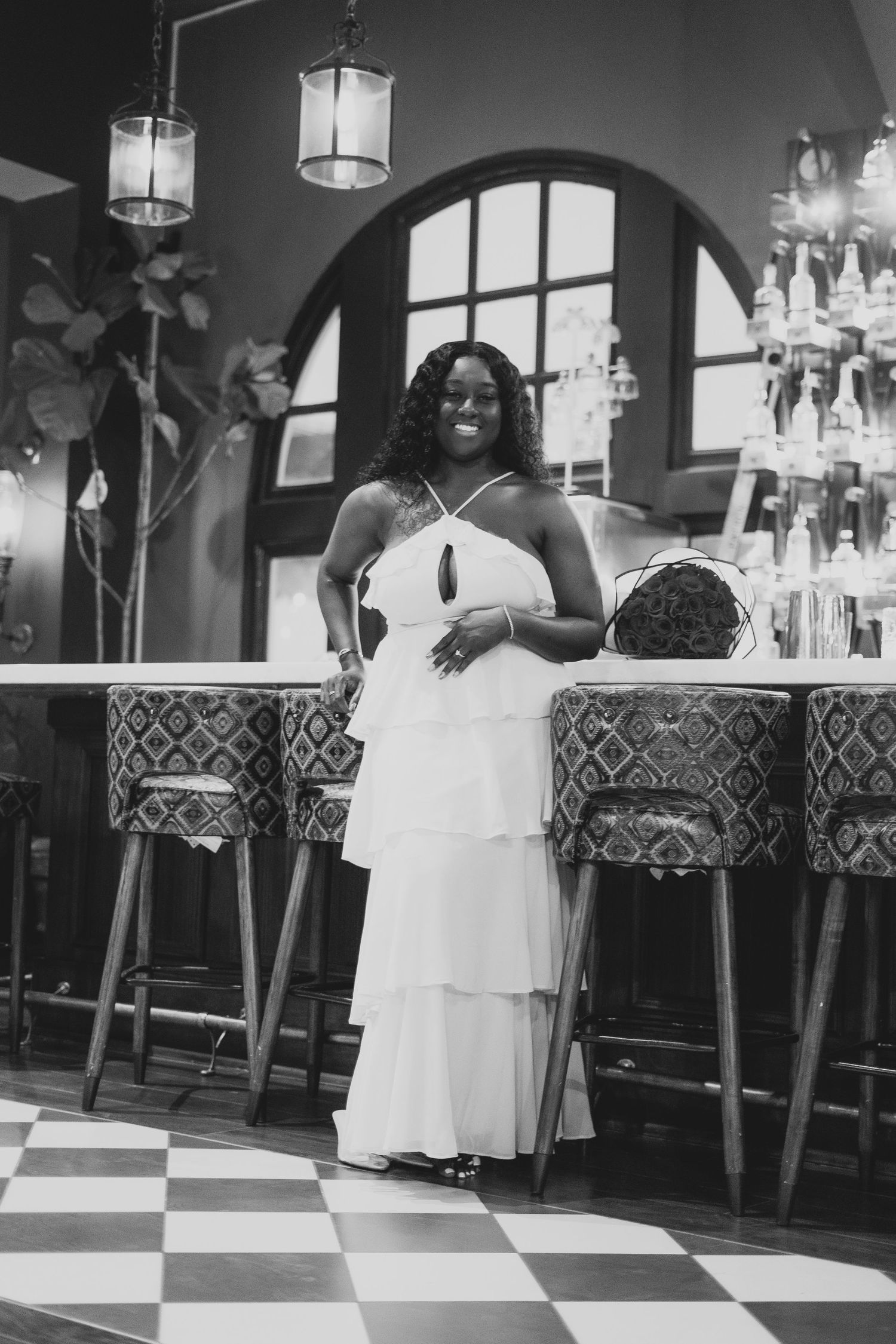 A black and white photo series showing a person in a white dress dancing on a checkered floor in a restaurant.
