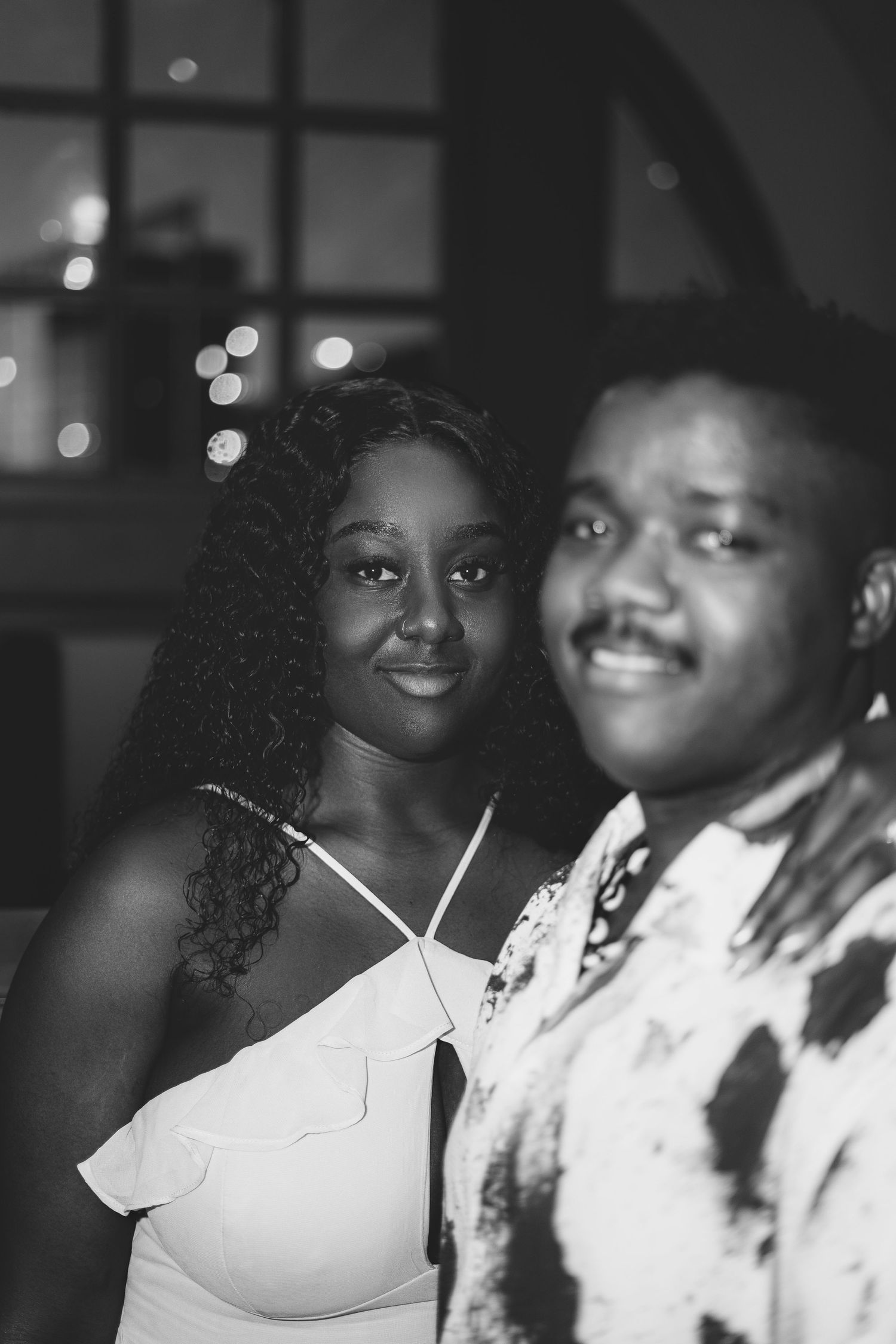 A black and white photo showing people in formal white attire posing together at a celebratory event.