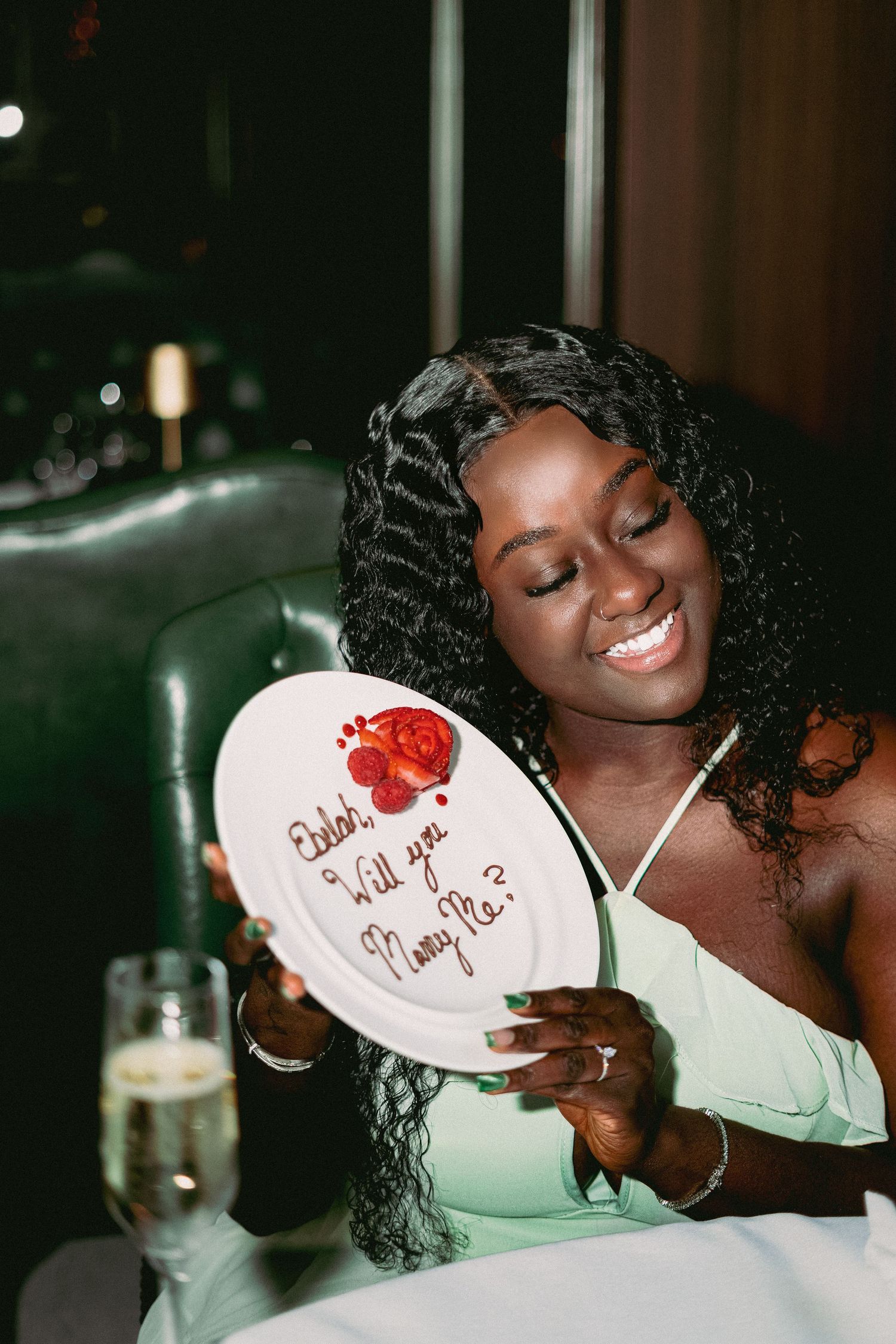 A person smiles while holding a heart-shaped note against a dark background in a sequence of candid photos.