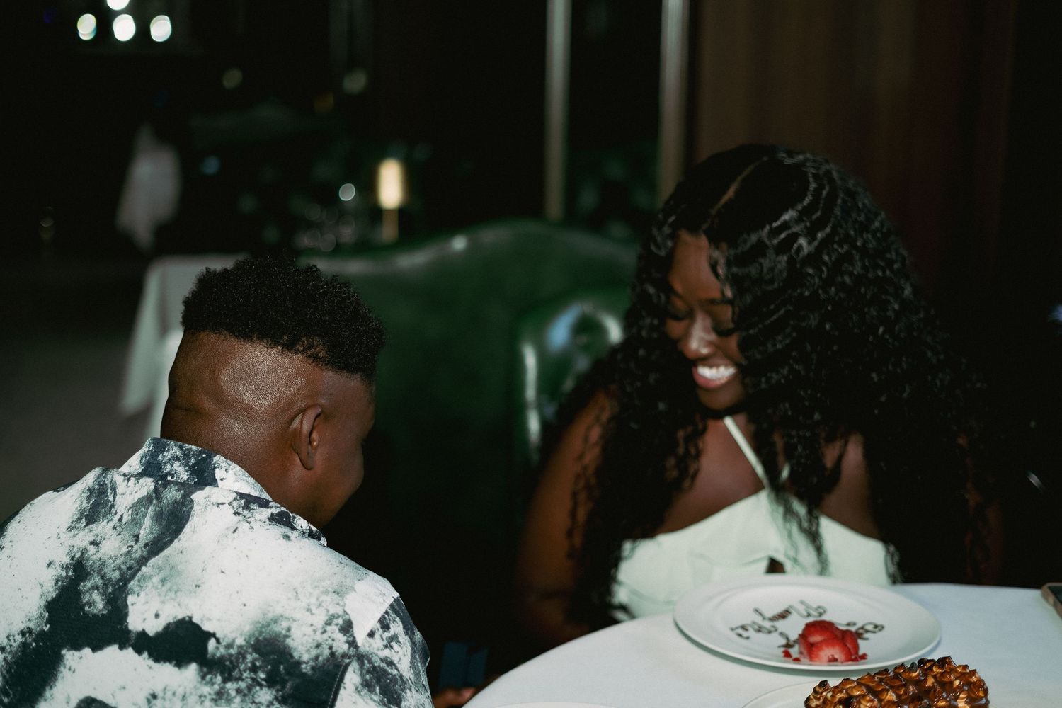 A couple shares an intimate moment during a celebration with cake and desserts.