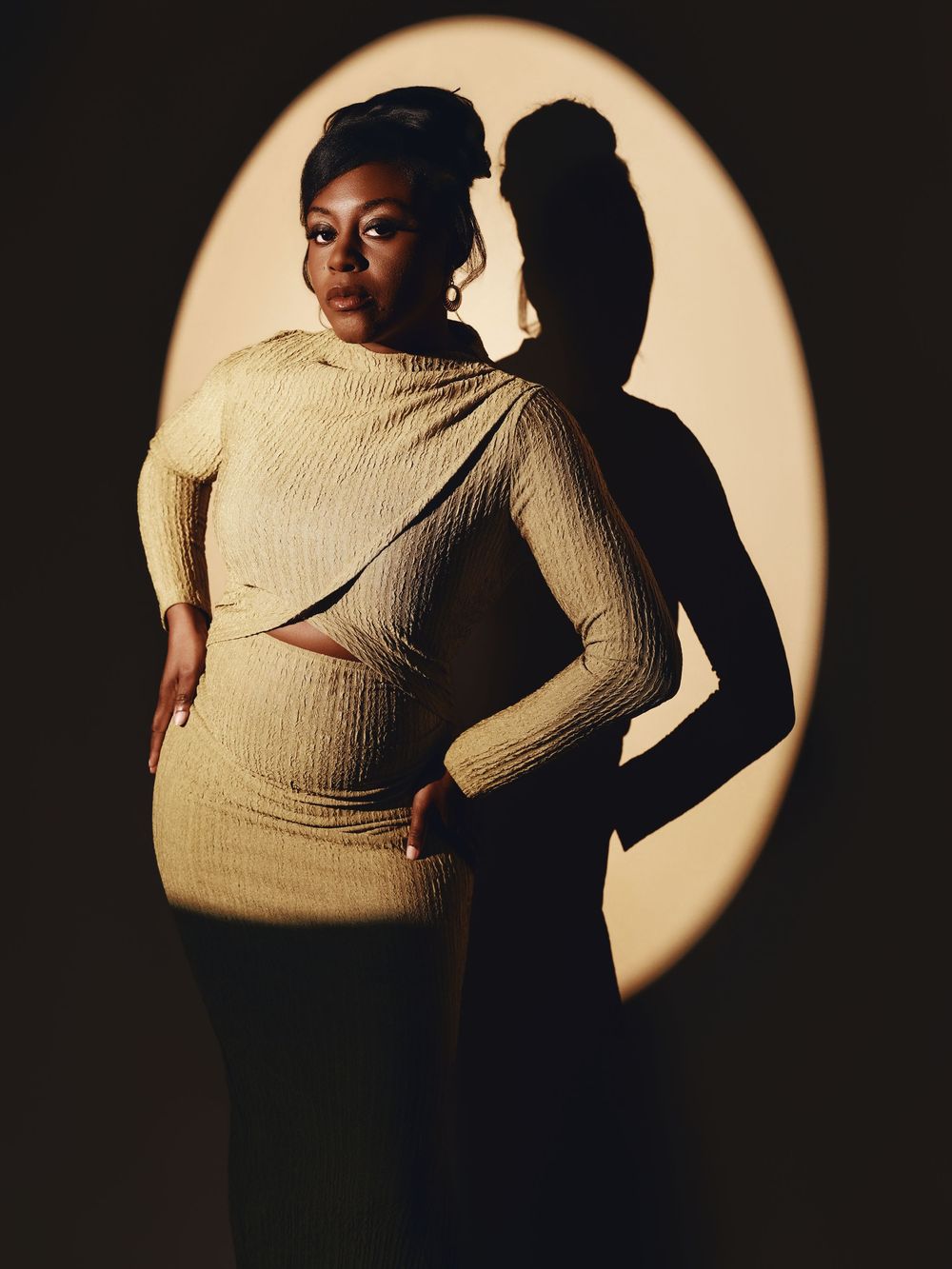 Artistic maternity photo series showing silhouette against circular spotlight in dramatic black and gold tones.