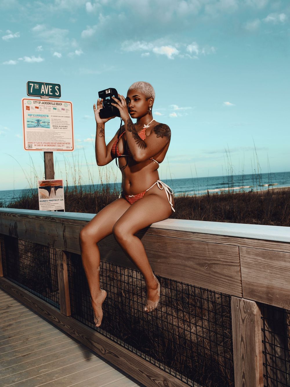 Photographer captures artistic shots from multiple angles on a wooden boardwalk by the beach at sunset.