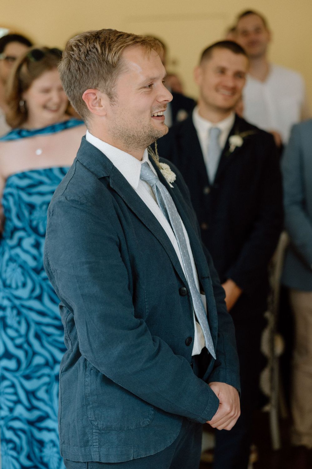 Wedding guests in formal attire gather in a room with blue decor.