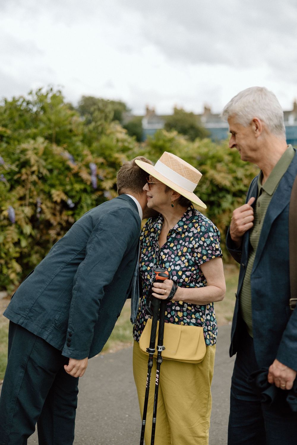 Woman in yellow skirt and floral top laughing while walking outdoors with companions.
