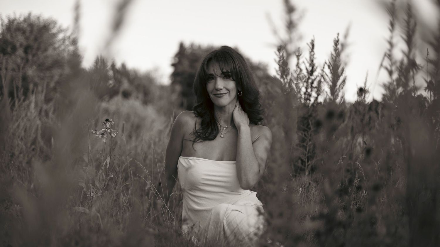 A series of black and white photos showing a person in a white dress posing outdoors among trees and foliage.