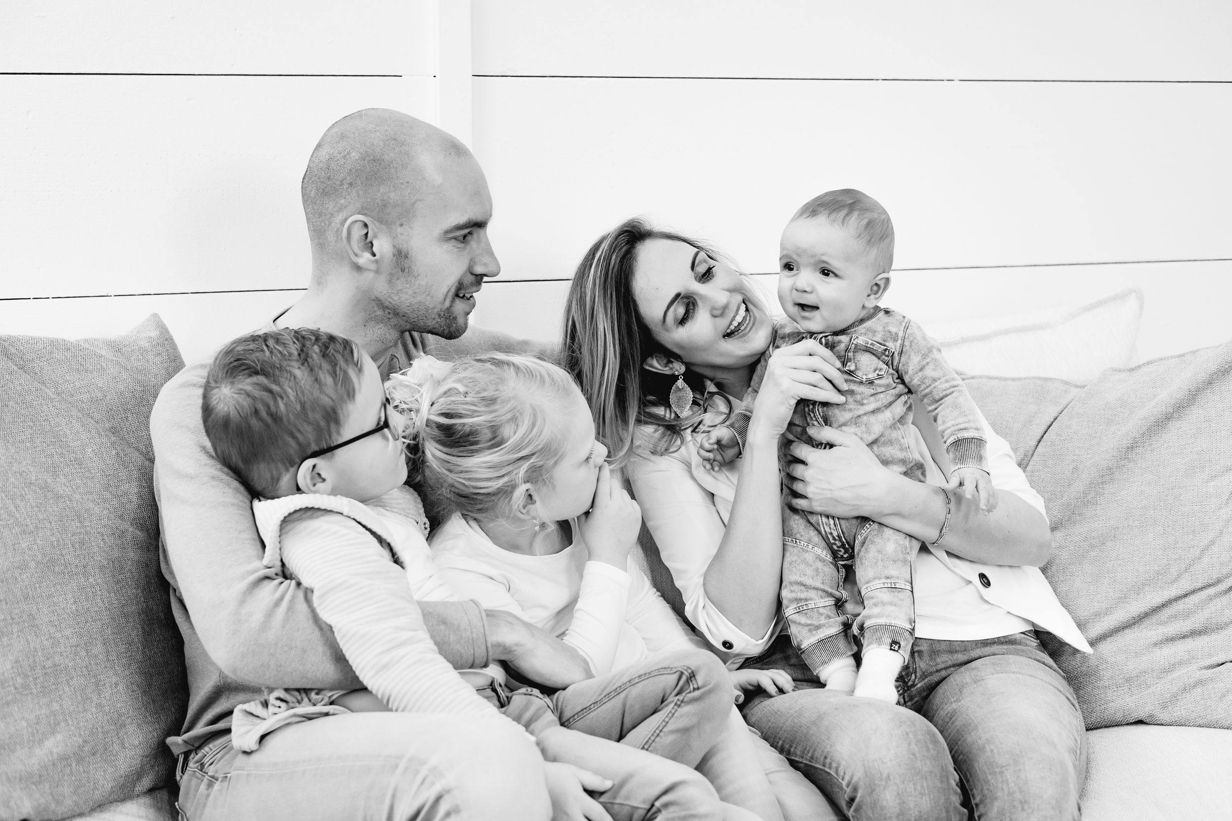 A cozy family moment captured in black and white as they relax together on a bed.