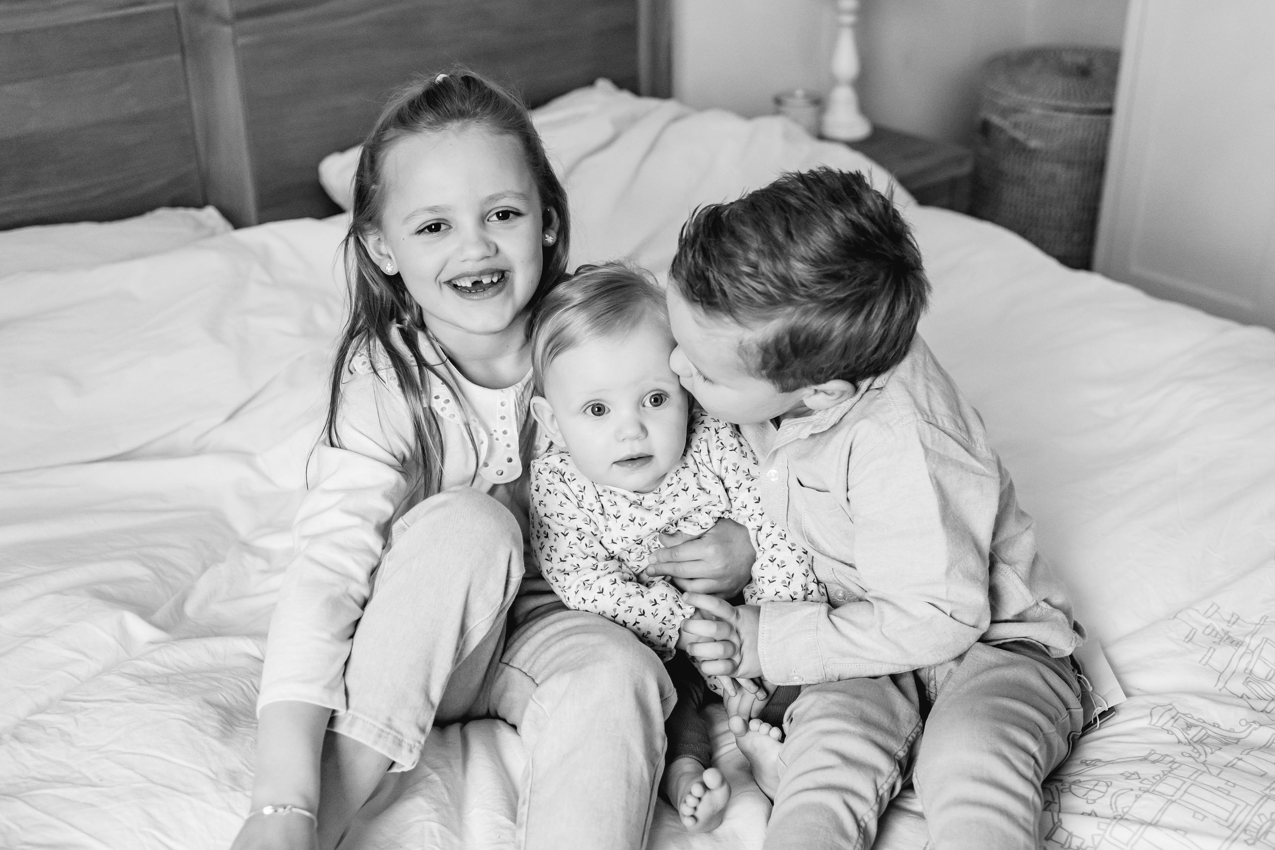 Family sharing joyful moments together on white bedding.