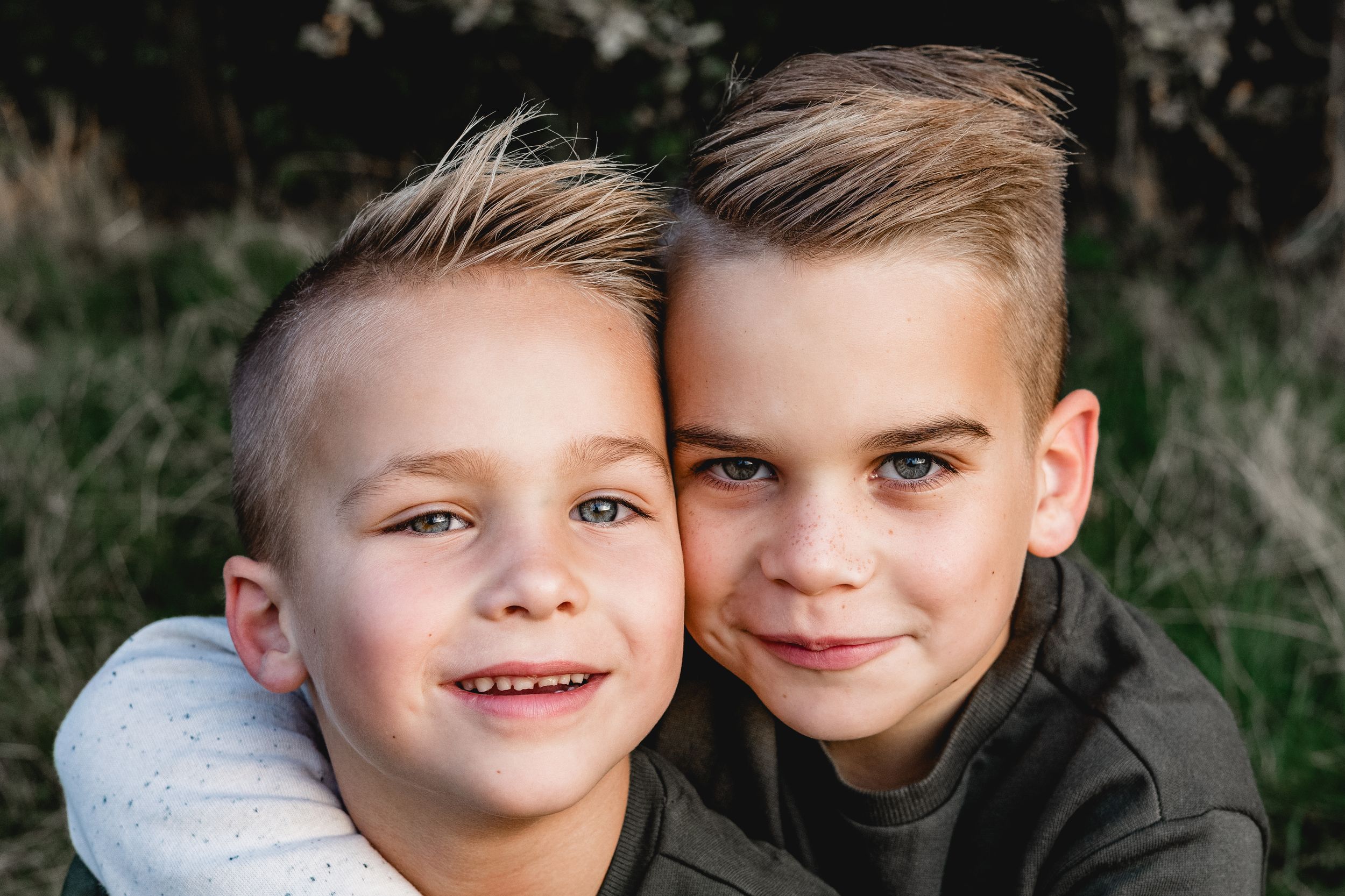 Children posing outdoors with natural greenery in background.