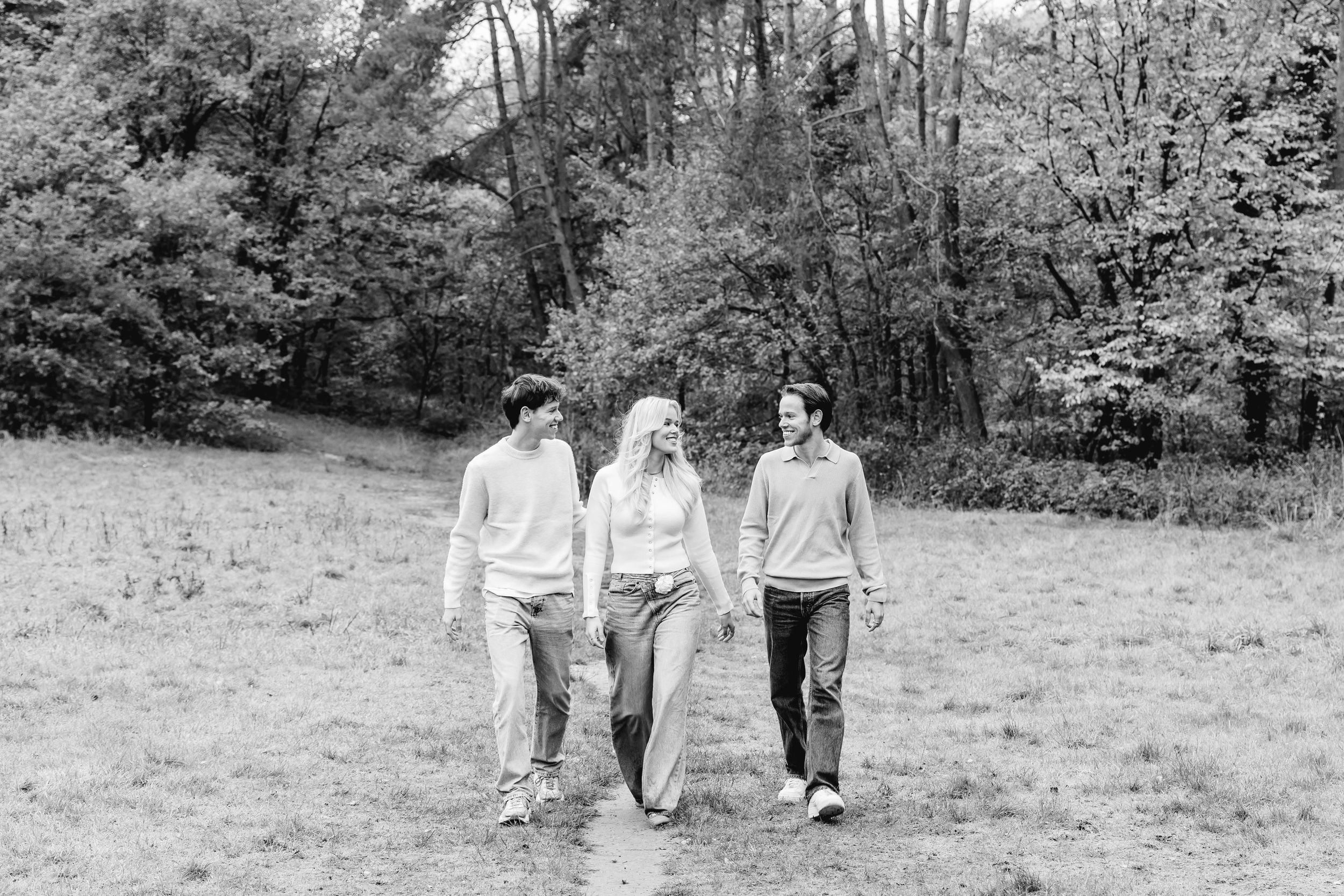 Black and white photo of a family walking together through a serene natural landscape.