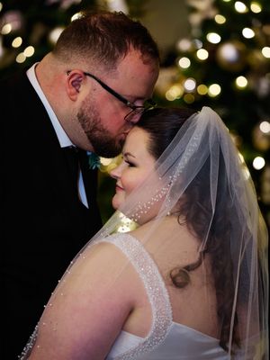 Romantic wedding couple shares an intimate kiss with twinkling lights and bokeh effect in the background.