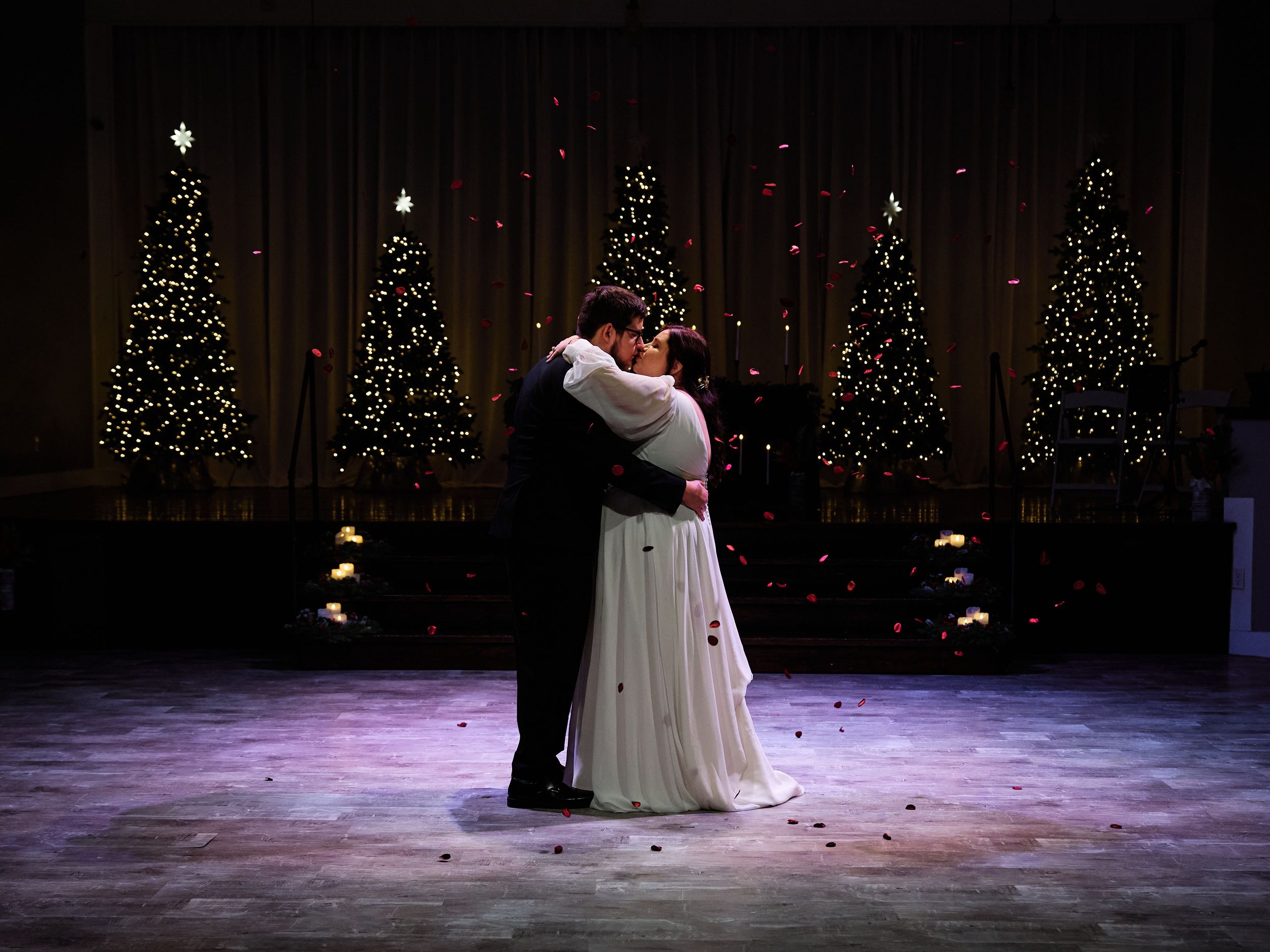 A couple performs a romantic dance on a dimly lit stage with twinkling lights in the background.