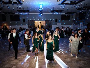 Wedding reception guests dance on an illuminated dance floor under blue lighting in an indoor venue.