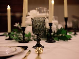 Elegant candlelit table setting with black candlesticks and greenery decorations for a formal dinner party.