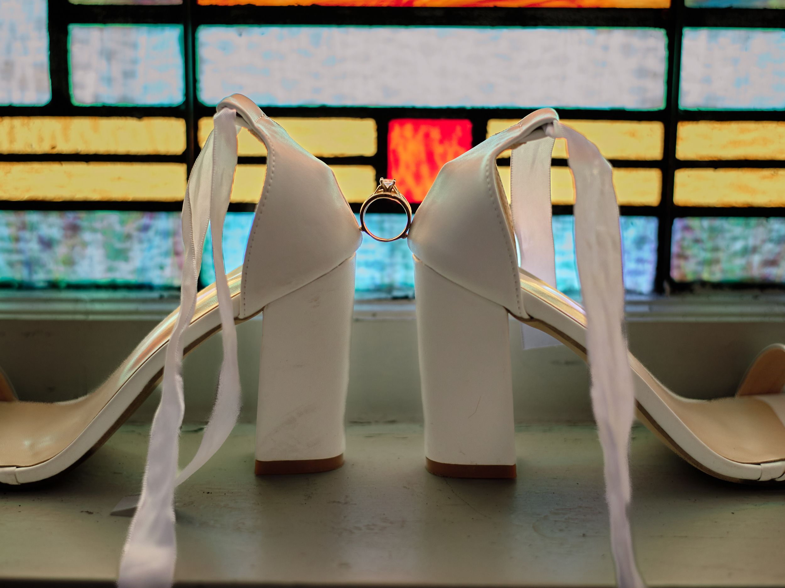 White wedding shoes displayed in a row against a colorful blurred background.