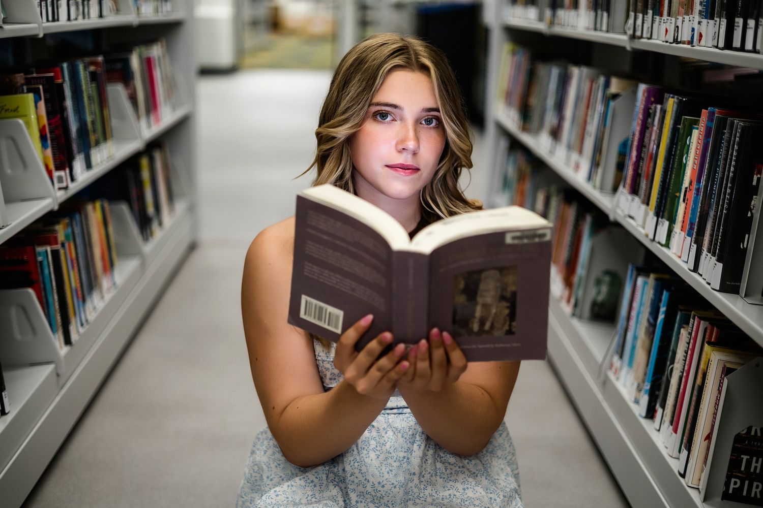 A series of photos showing someone reading a book while standing between library bookshelves.