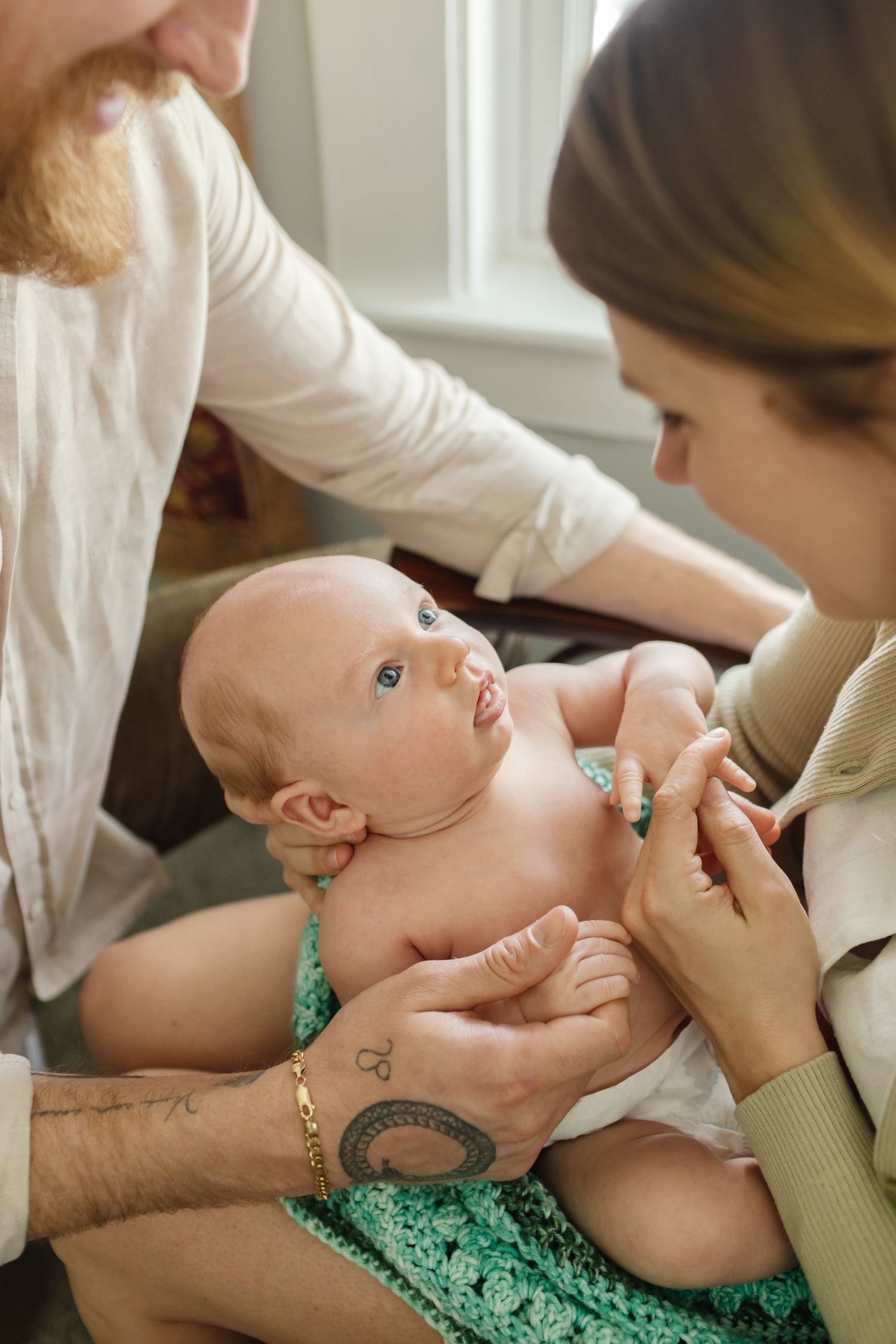 A newborn wearing a diaper gazes at his mother holding him in his nursery for newborn photos in the Seacoast, New Hampshire region.