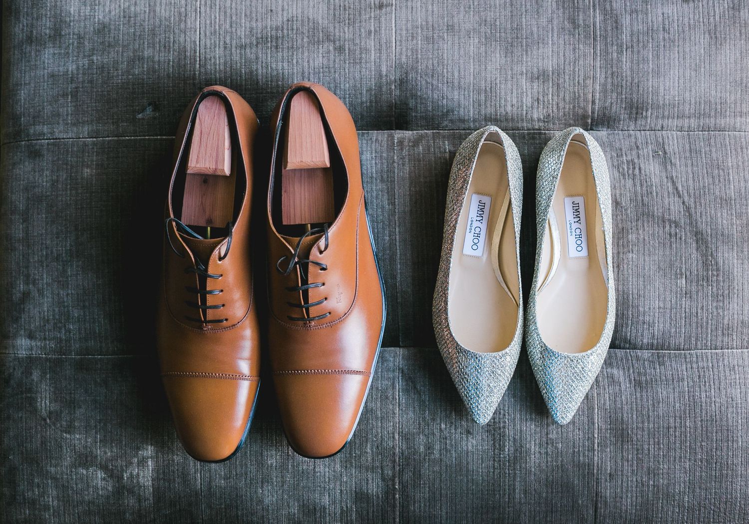 A collection of leather and suede dress shoes and oxfords arranged in a row on a gray textured surface.