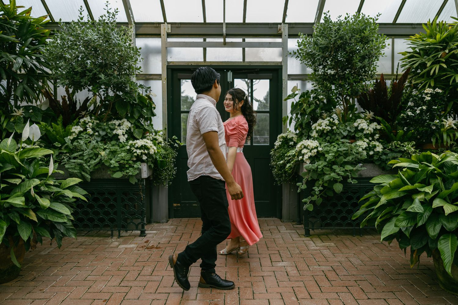 couple walking for photoshoot in greenhouse in asheville nc romantic flowers
