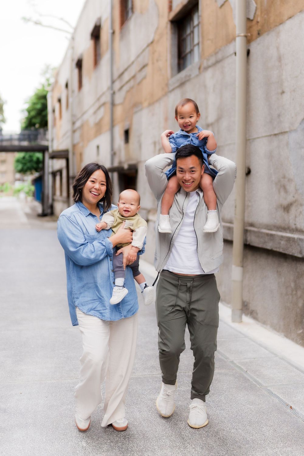 Family walking and playing together in an urban alley with stone buildings and concrete ground.