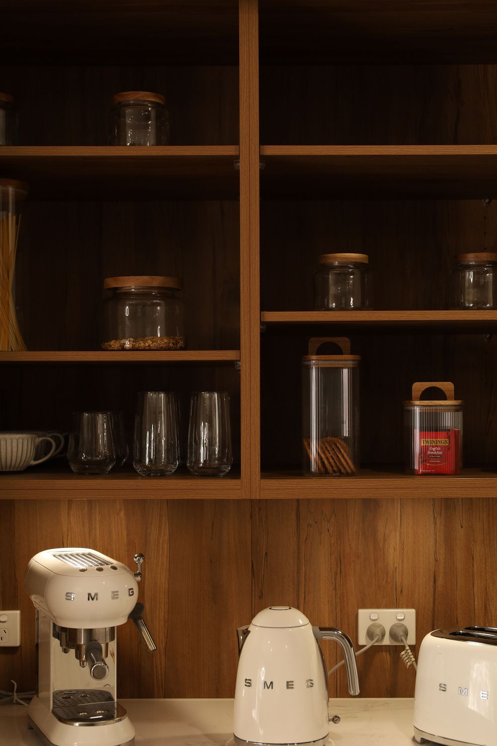 Wooden shelving unit displaying glass storage jars and white kitchen appliances.