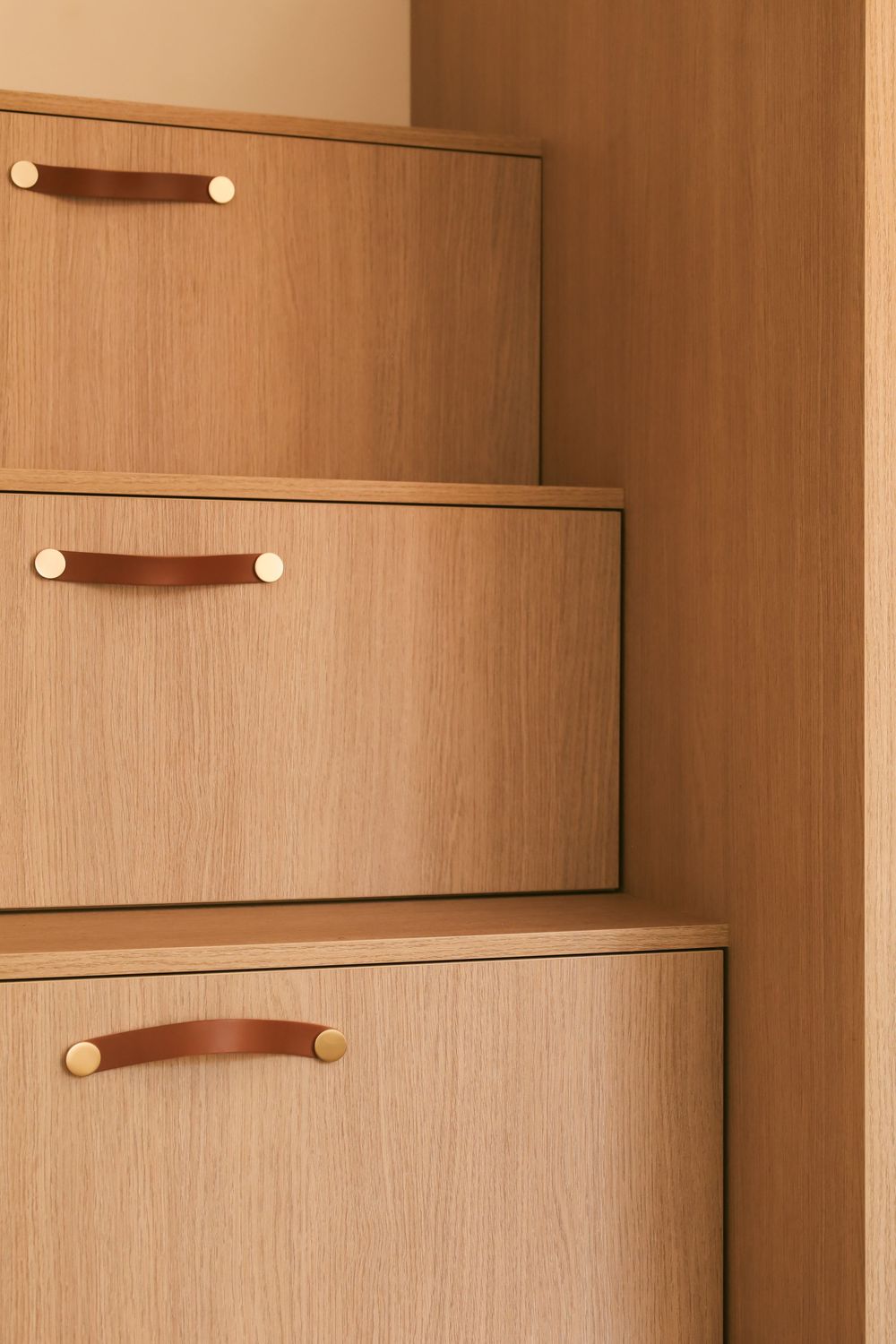 Modern wood cabinet with sleek leather pull handles and minimalist design features clean lines and natural tones.