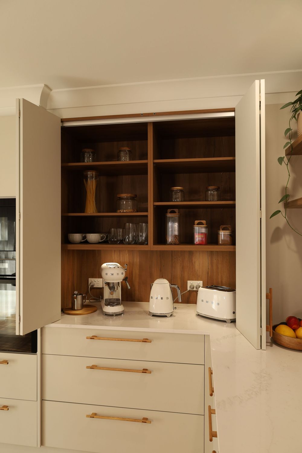 White kitchen cabinets with wooden shelving displays kitchenware and appliances in a contemporary design.