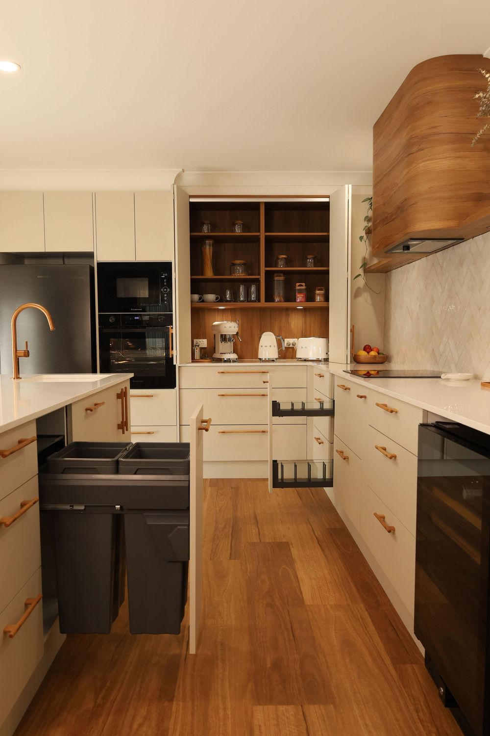Modern kitchen interior with white cabinets, wooden floors, and black countertops showing a sleek minimalist design.