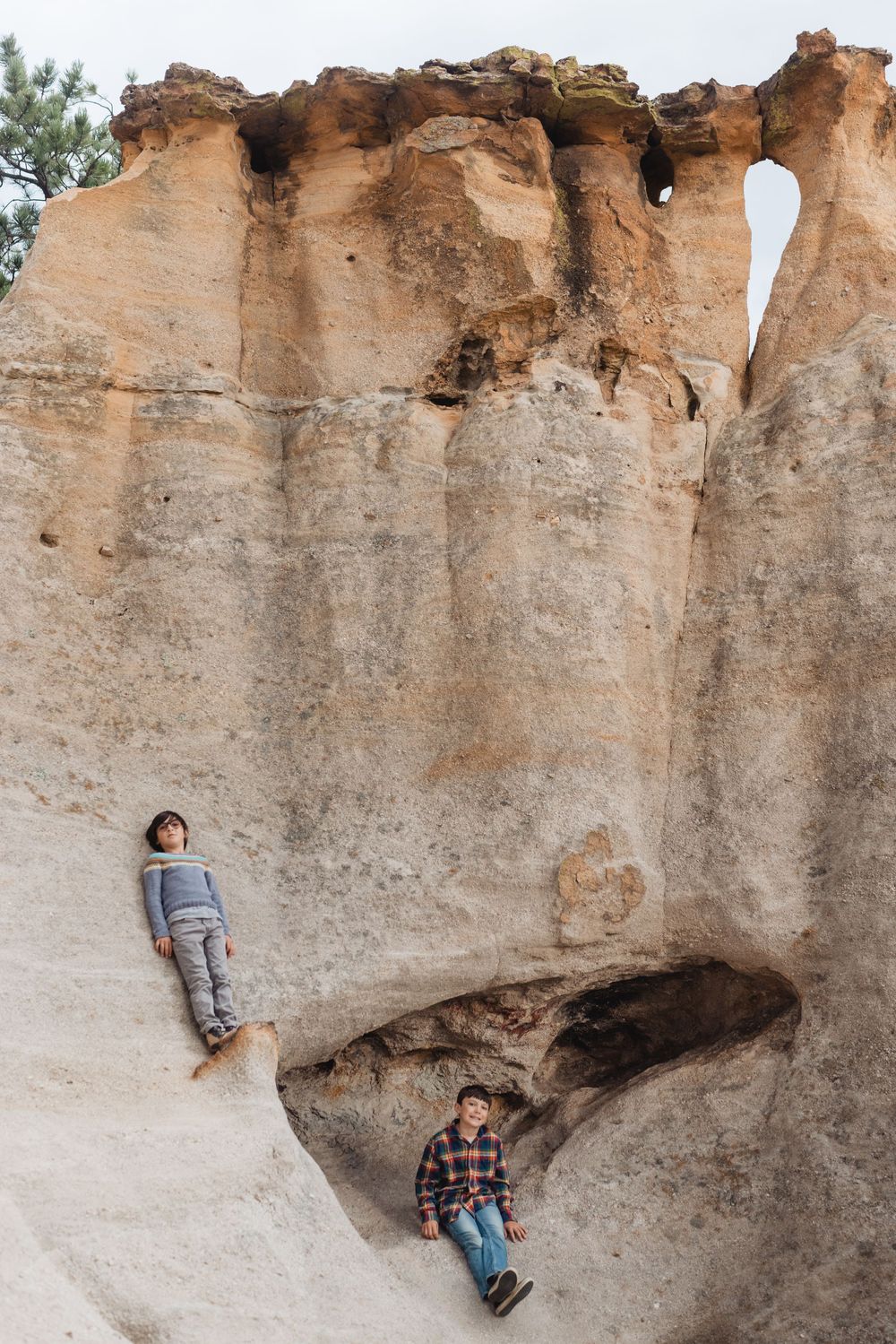 A person climbs along a natural limestone rock formation with multiple cave-like indentations.
