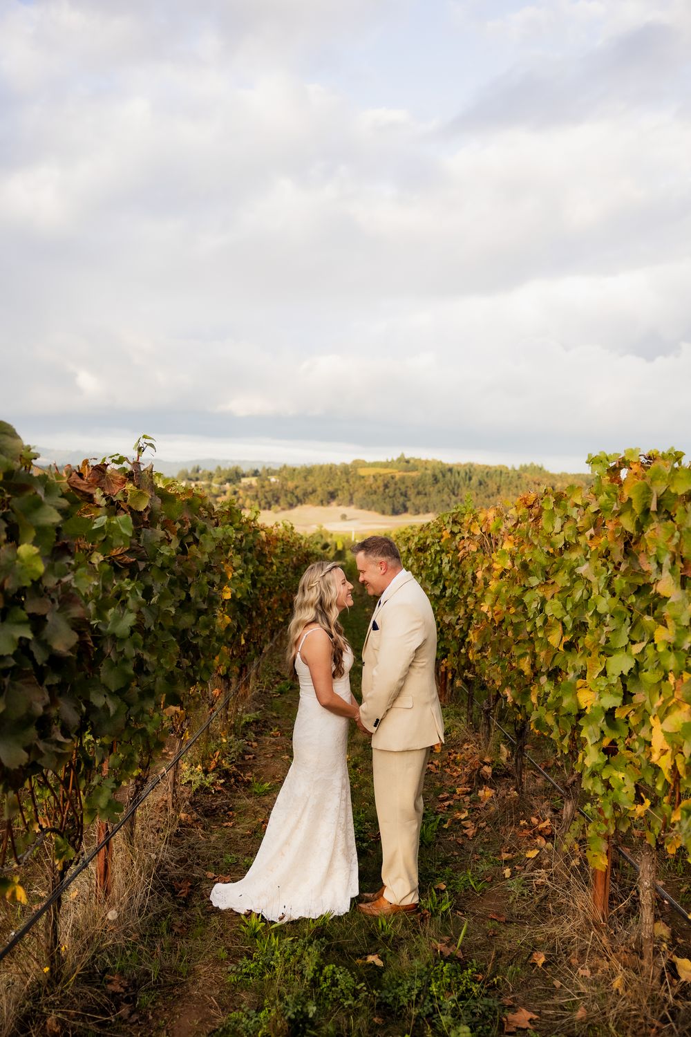 A couple shares an intimate moment among autumn vineyard rows during their wedding photoshoot.