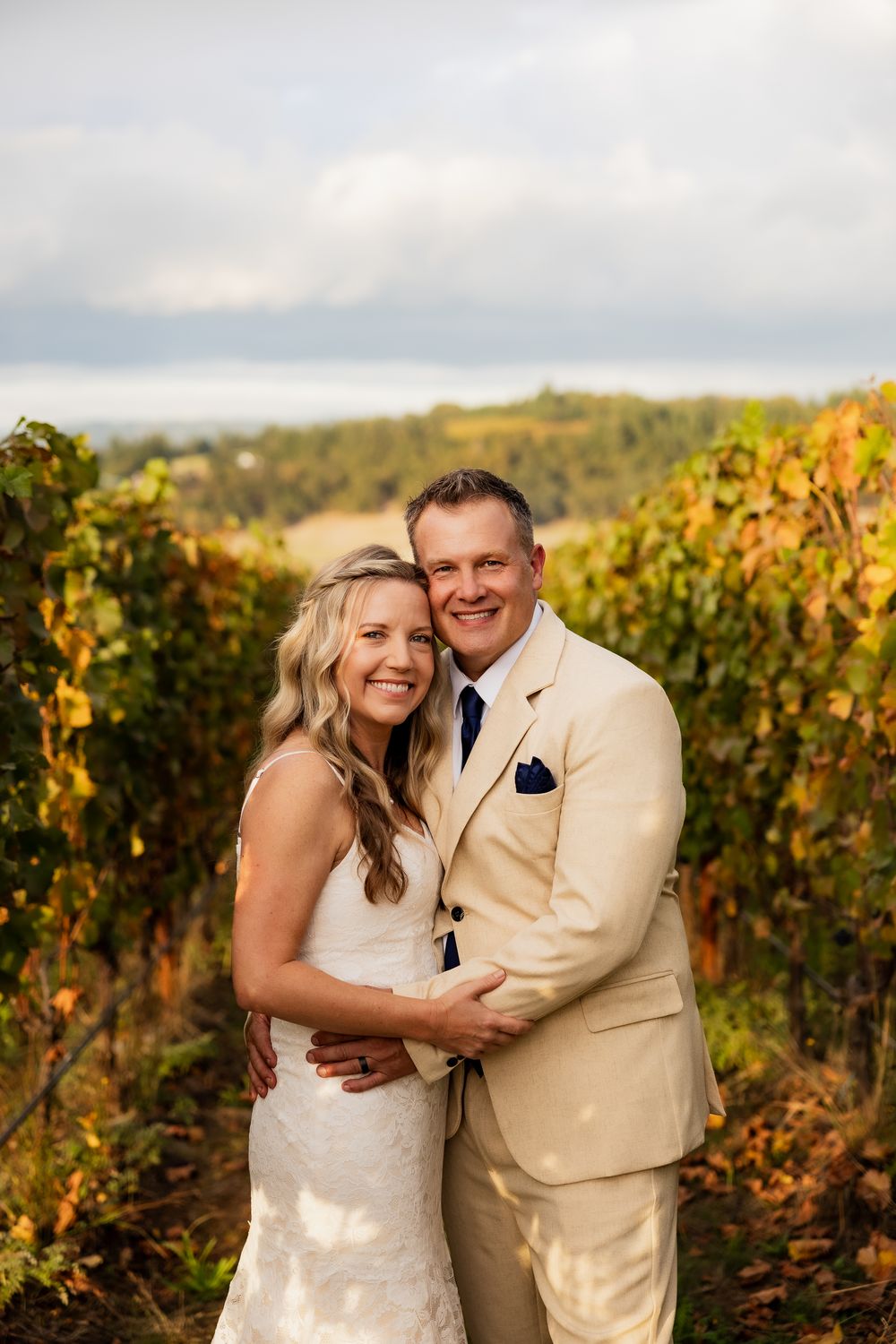 Couple shares joyful moment among autumn vineyard rows with golden foliage.