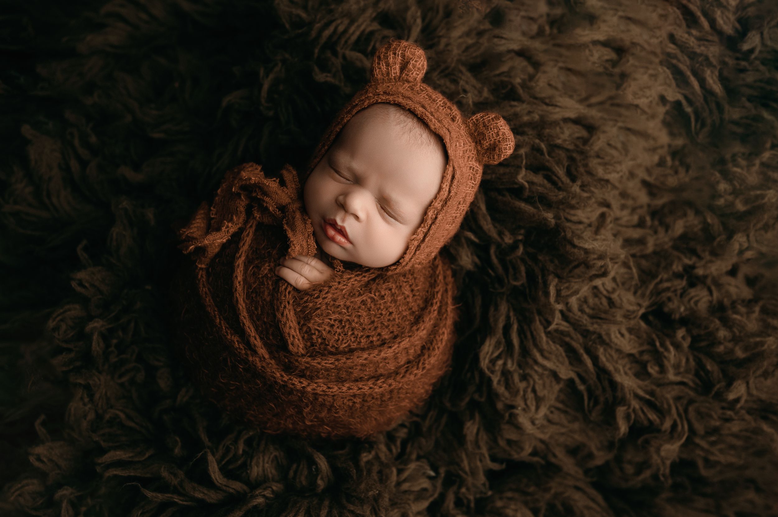 A series of artistic newborn photography shots showing peaceful sleeping poses in warm brown tones.